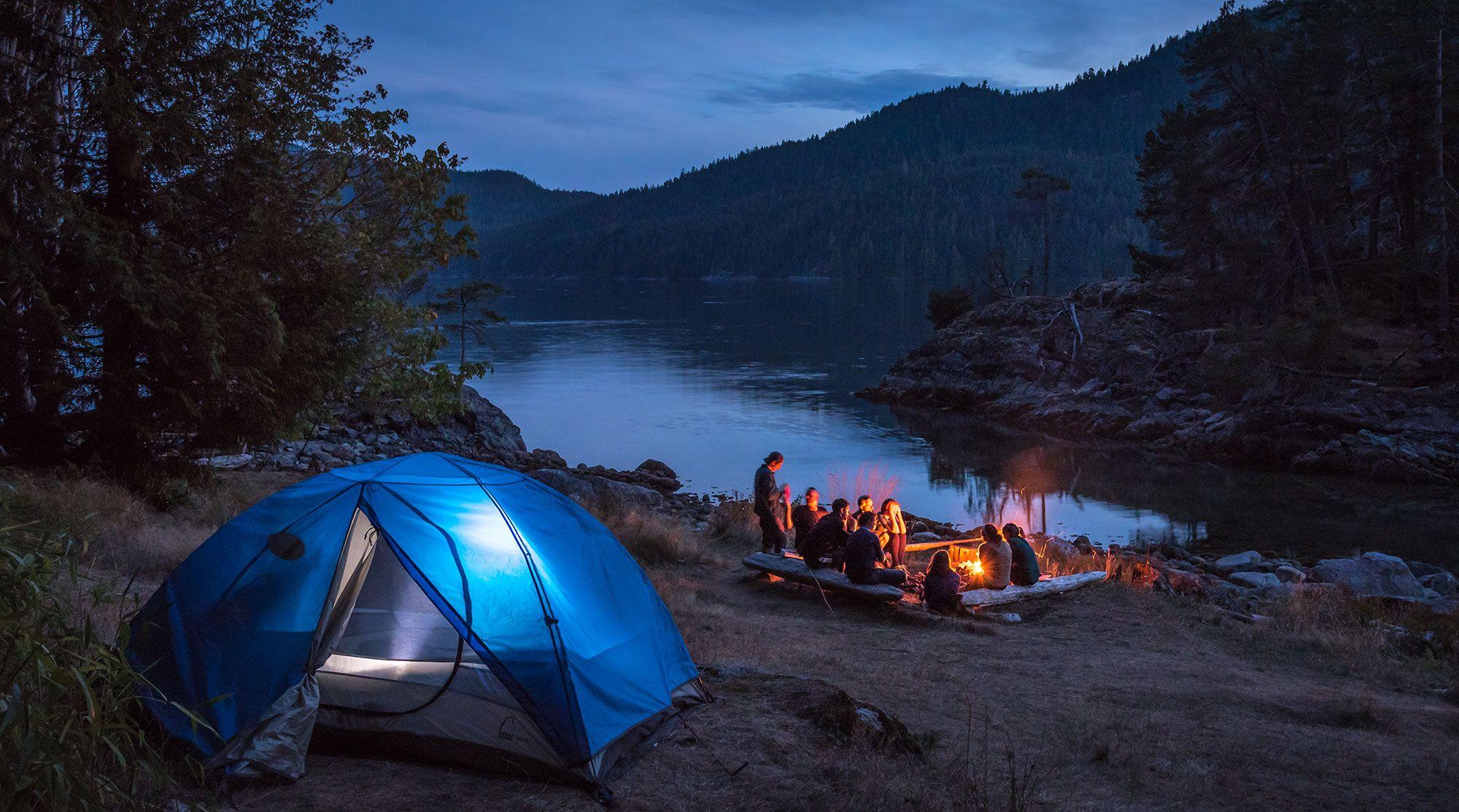 Camping scene with a blue tent by a lake at night