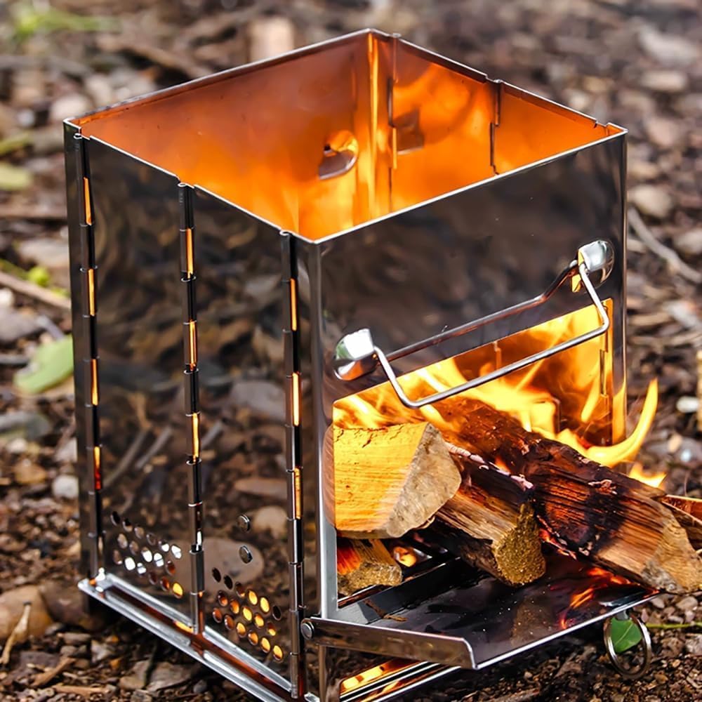 Metallic camping stove with flames and wood inside on a natural ground background