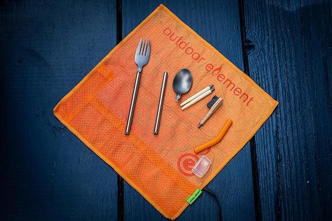 Orange mesh pouch with camping utensils on a dark wooden surface